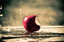 rain falling on an apple with a bite out of it