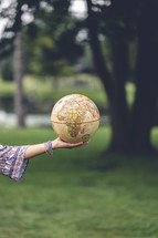 a woman holding a globe outdoors 
