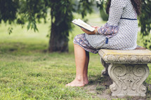 a woman sitting outdoors reading a Bible 