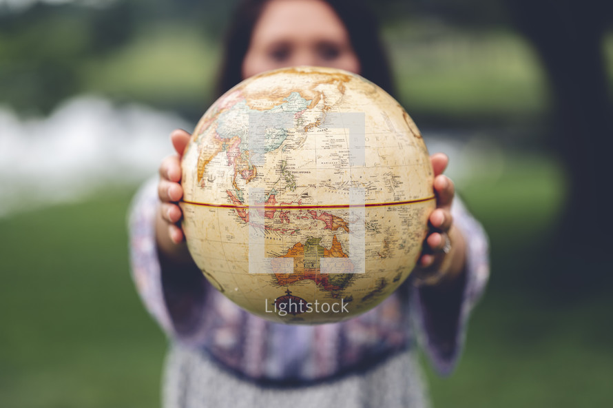a woman holding a globe outdoors 