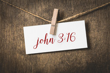 John 3:16 on white card stock hanging from a clothespin on a clothesline 