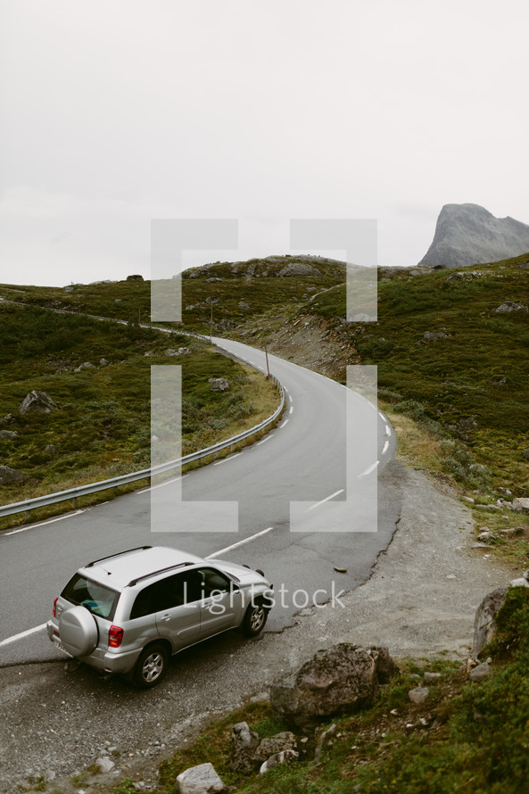 a car parked along the side of a curvy mountain road in Norway 