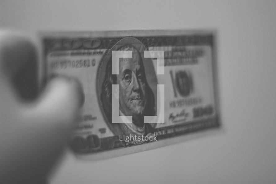 Hand holding a hundred dollar bill.