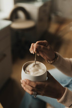 Woman stirring coffee with foam