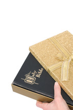 holding a Bible and a wrapped gift 