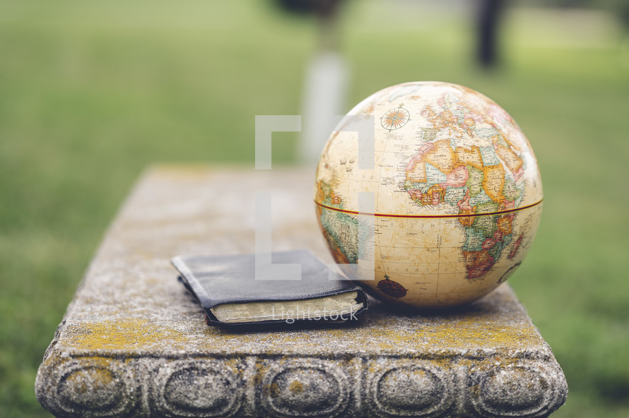 globe and Bible on a bench outdoors 