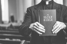 Priest hold closed bible in front of him