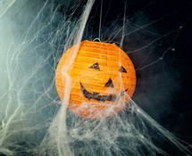 Pumpkin among cobwebs and fog on black background. Halloween image.
