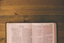 Bible open to Mark on a wooden table.