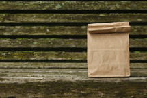 brown lunch bag on a wood bench 