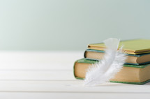 feather and a stack of books 