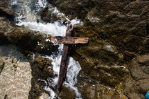 rugged cross on rocks and tide washing in 
