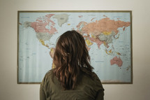 a woman standing in front of a world map 