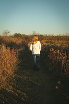 a teenager walking through a field 