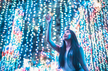 a woman touching Christmas lights 