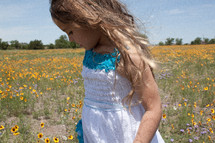 a young girl walking in a field of wildflowers 