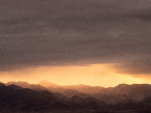 Light breaking through the darkness over rugged mountains