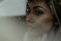 Woman's face behind rainy window
