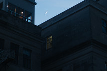 crescent moon over city buildings 