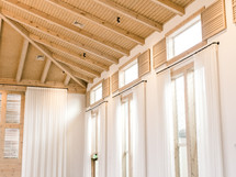 long curtains on windows and wood beams on a ceiling 