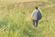 a man walking down a hill carrying a Bible 