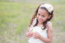 a smiling little girl holding a flower 