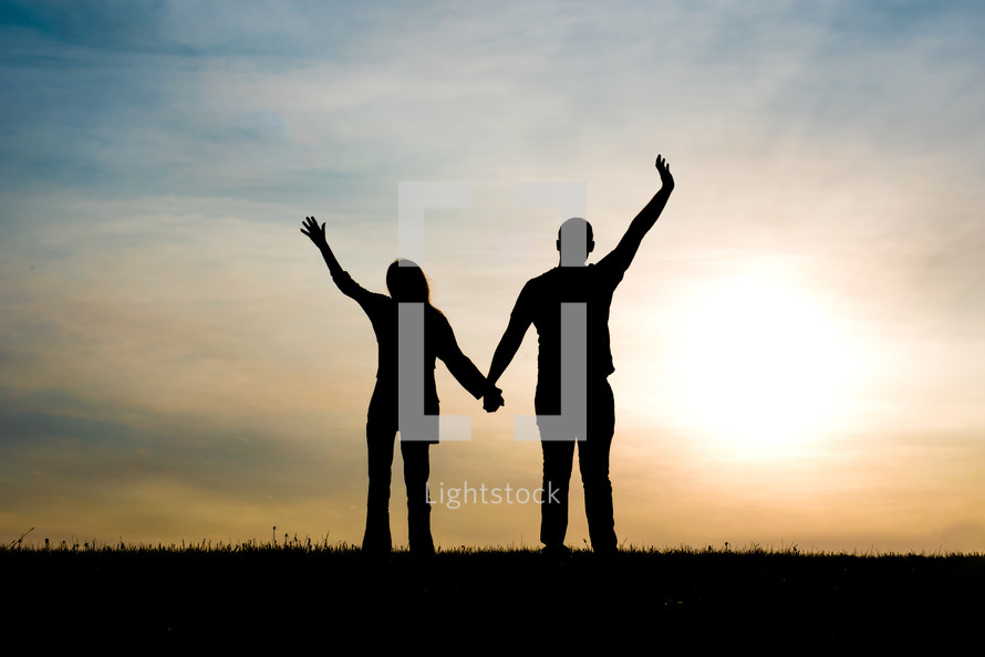silhouette of a couple with raised hands 