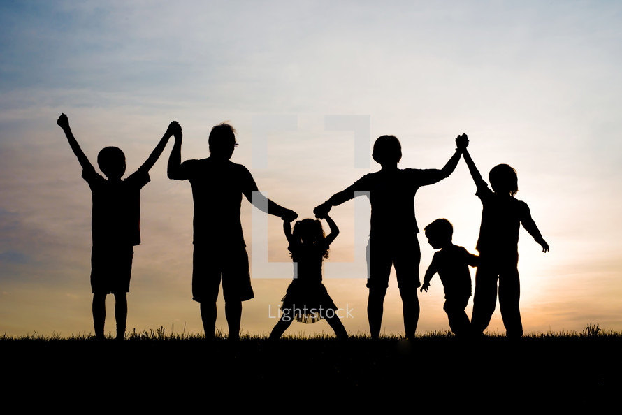 silhouette of a father holding hands with his children 