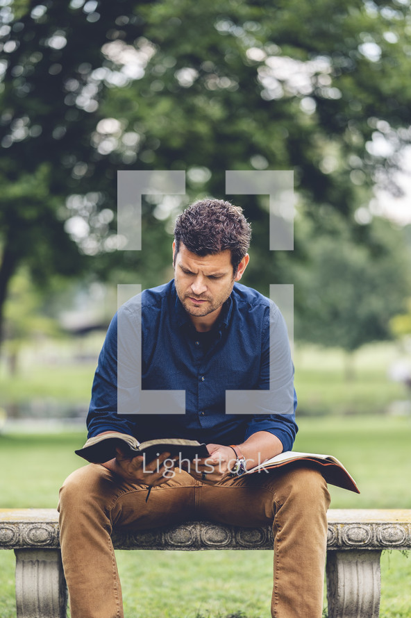 a man sitting outdoors reading a Bible 