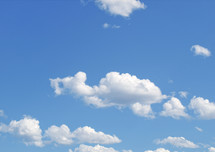 Fluffy white clouds in a blue sky - background