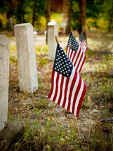 American flags beside very old grave markers 