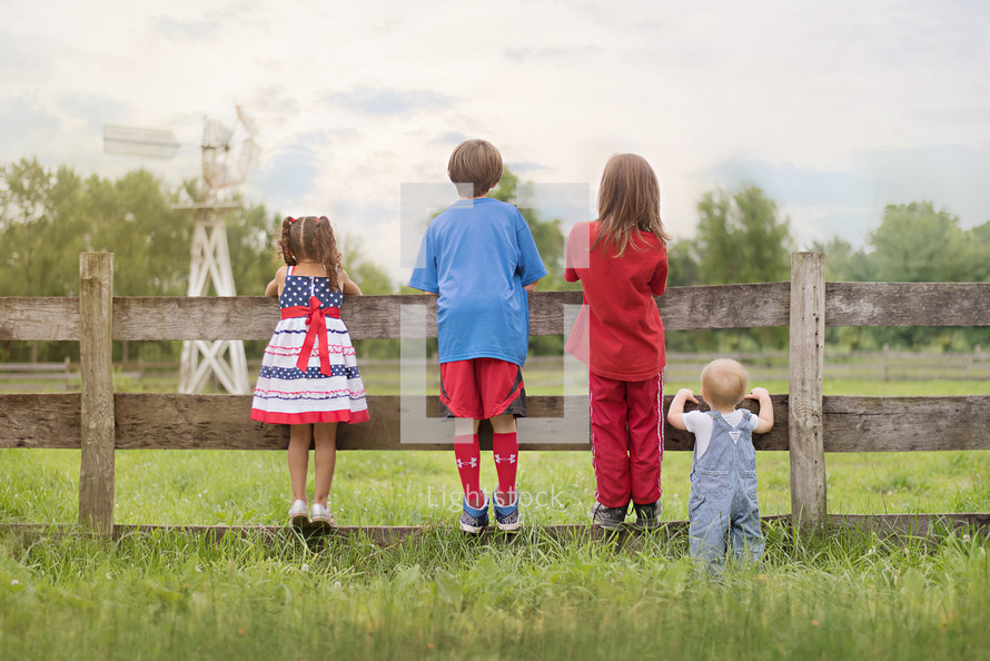family in patriotic colors looking over a fence 