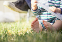 infant boys bare feet sitting in the grass 
