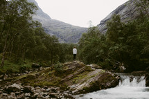 a woman standing by a waterfall in Norway 