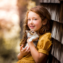 a smiling girl holding a kitten 