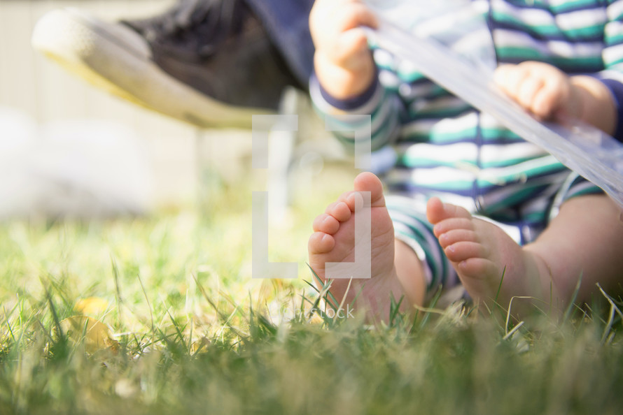 infant boys bare feet sitting in the grass 