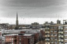 water drops on windows overlooking a city below 