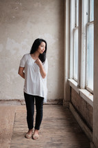 young Asian woman standing in front of a window 