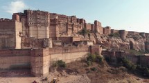 Mehrangarh Fort on a sunny day with birds flying around in Jodhpur, Rajasthan, India - Aerial Ascending establishing shot