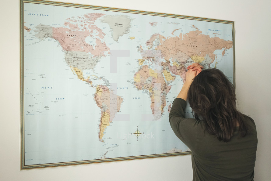 a woman praying over a world map 