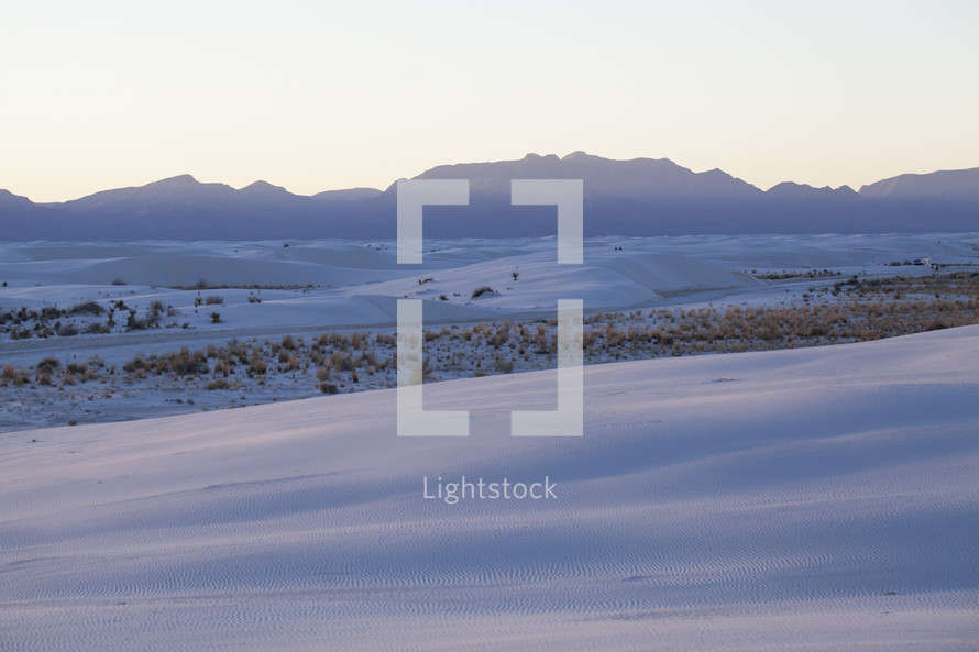 Snow covered tundra with a silhouette of a mountain range on the horizon.