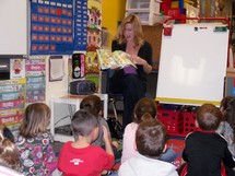 A teacher reading a story book to her kindergarten classroom 