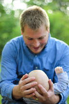 Man cradling his infant son outside.