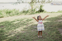 A smiling little girl with outstretched arms.