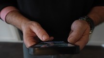 Man looking and scrolling through a cell phone. Close Up. 