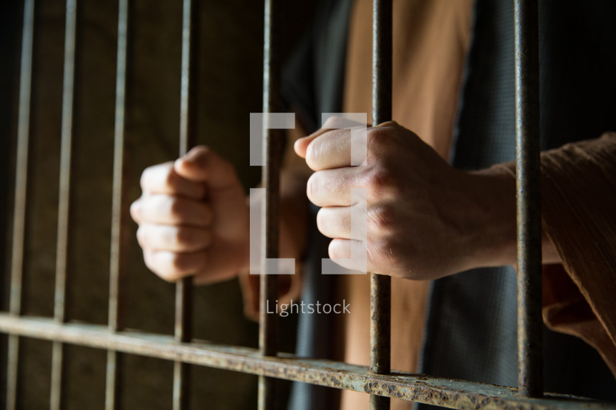 A man holds onto prison cell bars.