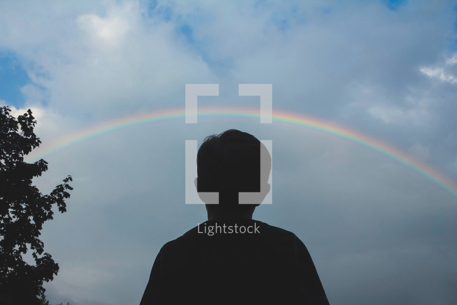 silhouette of a boy under a rainbow 
