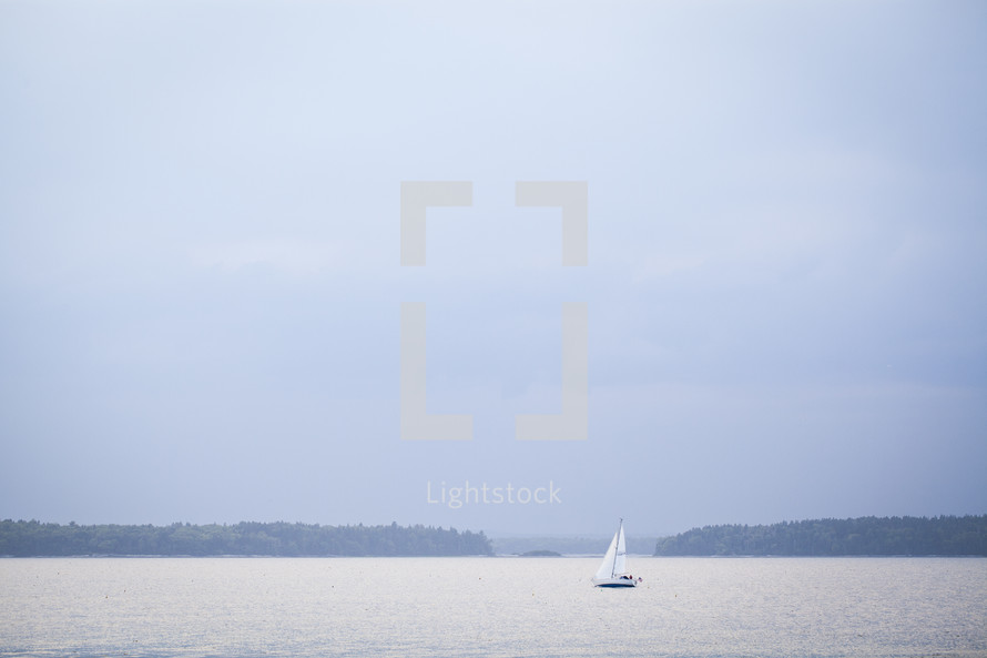 Sailboat on the ocean water at dusk.