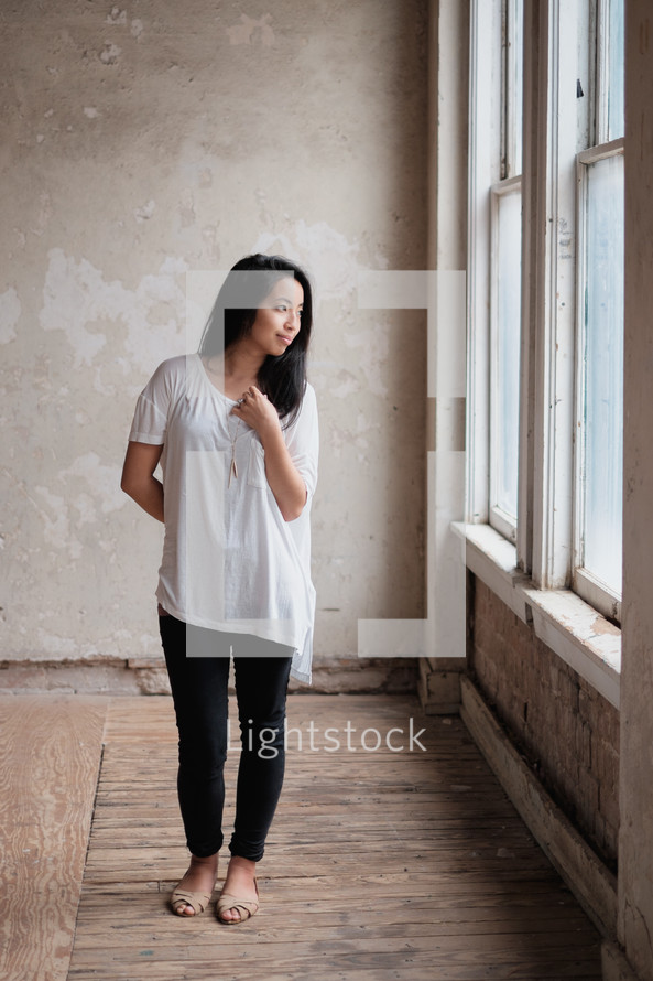 young Asian woman standing in front of a window 