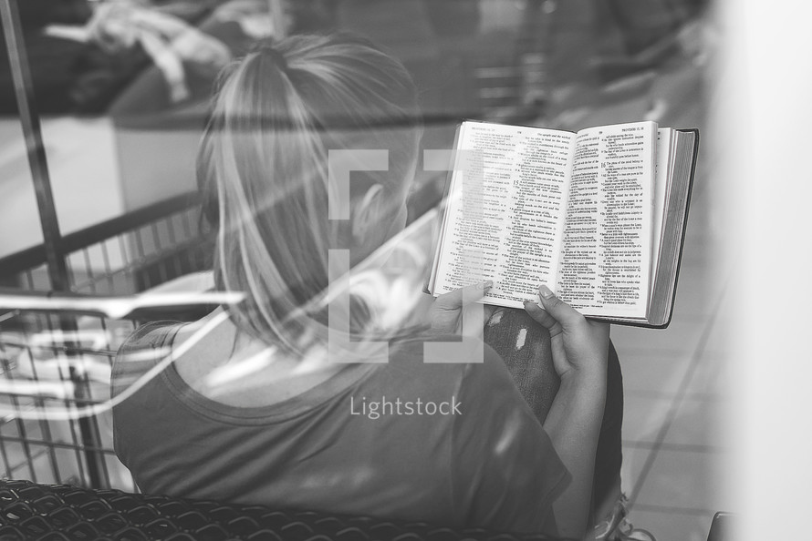 a woman reading a Bible at a laundry mat 